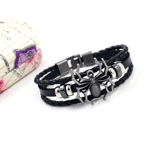 Detail view of retro spider charm on multi-layer braided leather bracelet with metal clasp