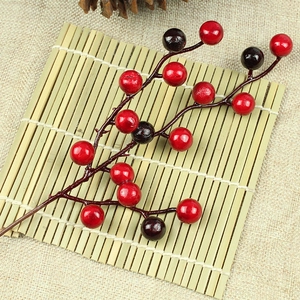 Macro shot of artificial red and burgundy foam berries on natural textured stems