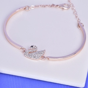 Detail of rose gold swan bangle with sparkling rhinestones on a white cushion