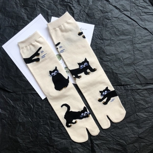Close-up of cream Tabi socks with black cat patterns on textured artistic background