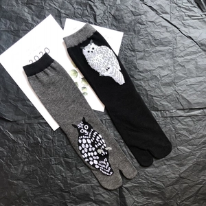Detailed view of grey and black tabi socks featuring knitted owl patterns and ribbed cuffs