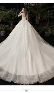 Lace-up back detail of a luxury white lace wedding dress with long sequined tulle train