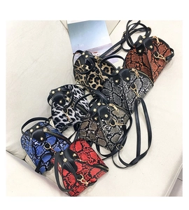 Detailed overhead view of multiple mini leopard and snake print crossbody bags on a sofa