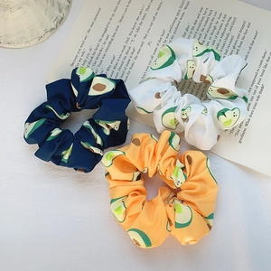Three-pack of avocado print scrunchies in navy, white, and yellow satin fabric