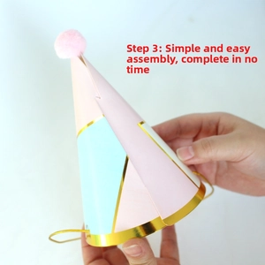 Detail of pink and blue party hat with a pom-pom and elastic band assembly process