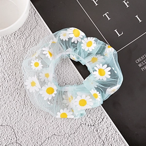 Detail of light blue mesh hair scrunchie with white daisy floral prints on stone texture