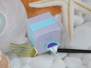 Maritime blue striped candy box with sailboat detail on white pebbles and seashells