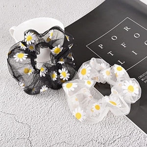Black and white daisy print mesh scrunchies set on a minimalist textured background