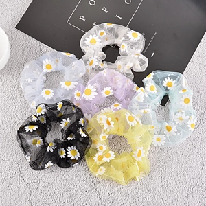 Detailed flat lay of six colorful daisy print mesh scrunchies in various pastel shades
