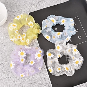Detail view of colorful mesh scrunchies featuring embroidered daisy patterns in four soft colors