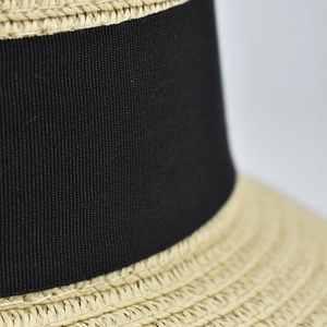 Close-up of the natural straw weave texture and black grosgrain ribbon on the sun hat