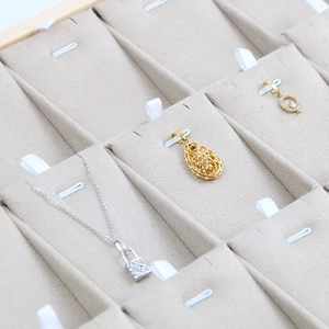 Elegant gold pendant necklaces displayed on a premium beige velvet jewelry organizer tray