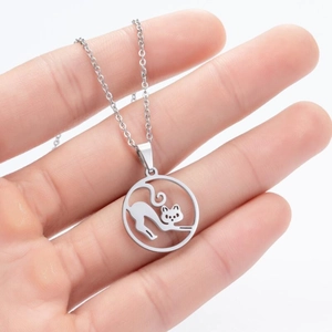 Detail of a laser-cut stainless steel hollow cat pendant necklace held by hand