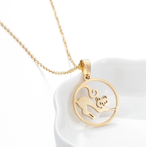 Close-up of golden stainless steel necklace with a hollow cat silhouette pendant on ceramic