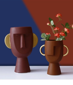 Dettaglio artistico di vasi viso in ceramica opaca rosso scuro e marrone con oro