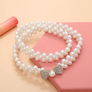 Elegant double-row pearl belt with a gold rhinestone bow accent on pink prop