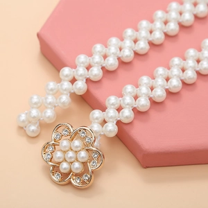 Detailed close-up of a pearl waist chain featuring a gold floral buckle with rhinestones