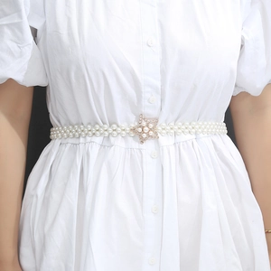 Detailed shot of an elastic pearl waist belt featuring a gold rhinestone starfish buckle