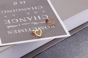 Detail shot of heart-shaped hollow stud earrings in gold and rose gold finishes