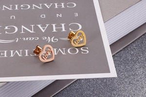 Detail of hollow heart stud earrings in gold and rose gold with love letter engraving