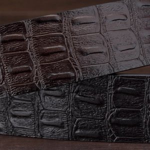 Men's leather belts with crocodile pattern in black and brown on wooden background