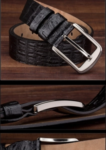Detail of black crocodile texture leather belt with silver metal pin buckle on wood