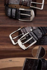 Macro detail of men's leather belt showing crocodile texture and metal buckle on wood