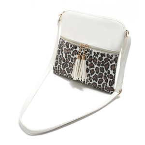 Close-up of leopard print crossbody bag featuring dual tassels and gold zipper detail