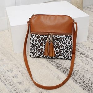 Detail of crossbody bag featuring leopard print panel and dual brown leather tassels