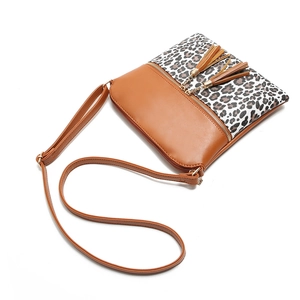 Detail of leopard print crossbody bag with dual tassels and adjustable shoulder strap
