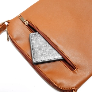 Detail showing the front zipper pocket of a brown leather crossbody bag with gold hardware