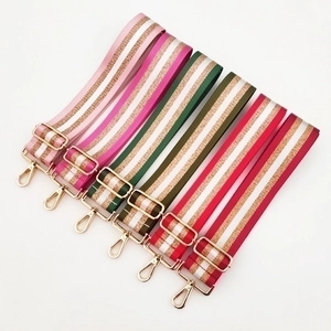 Detail of multi-colored striped canvas bag straps with polished gold metal swivel hooks