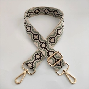 Close-up of ethnic jacquard beige shoulder strap with gold swivel hooks and geometric pattern