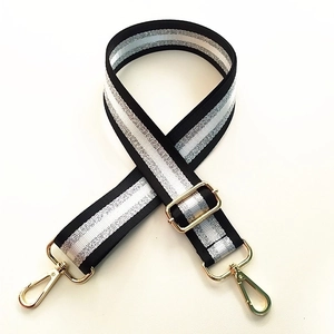 Detail of adjustable black and white striped bag strap with gold glitter metallic hardware