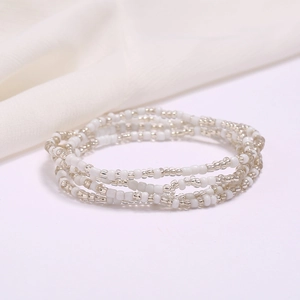 Handmade multilayer white and silver seed bead waist chain on soft white fabric background