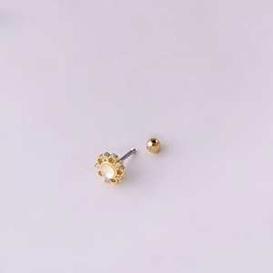 Golden flower cartilage stud earring with pearl and diamonds on pink background