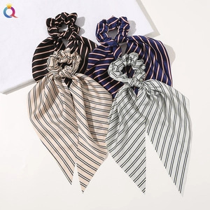 Detailed view of four silky satin hair scrunchies with long ribbons and striped patterns