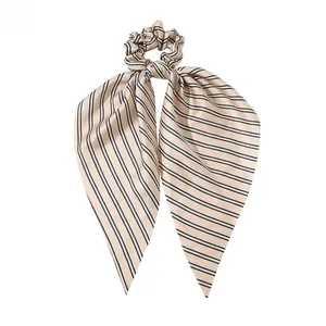 Detail of silk satin scrunchie with long ribbon featuring blue and yellow stripes