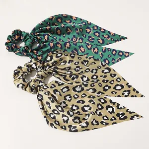 Detail of satin leopard print hair scrunchies with long ribbons in green and champagne gold