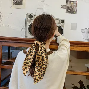 Detail of silk leopard print satin scrunchie bow tied on hair in vintage setting