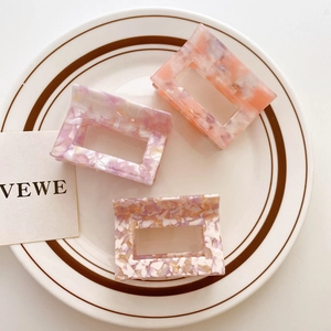 Three rectangular acetate hair claws with marble texture in pink, purple, and mixed colors