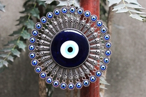 Close-up of blue evil eye wall decor featuring an intricate silver metal filigree frame