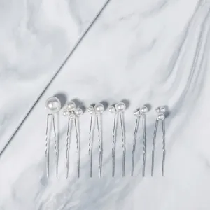 Flat lay of 6-piece pearl U-shaped hairpins with silver finish on marble background