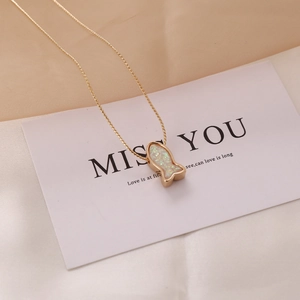 Close-up of gold mermaid pendant with colorful opal inlay on a gift card background
