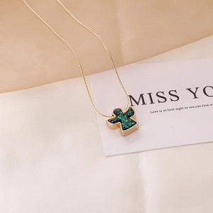 Detail of angel pendant with emerald green inlay on a golden chain necklace