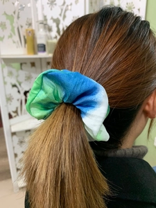 Detail shot of tie-dye fabric scrunchie in blue and green gradient on ponytail hair