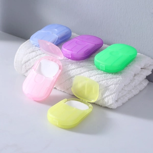 Portable travel paper soap sheets in colorful mini cases on a soft white towel