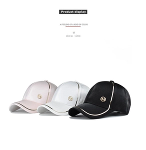 Detailed view of satin baseball caps with gold trim and M logo in pink white and black