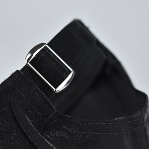 Detail of adjustable silver metal buckle and textured fabric on back of black baseball cap