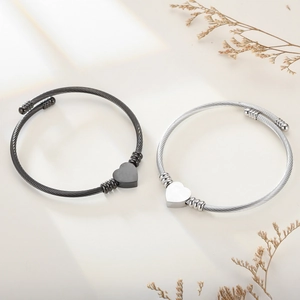 Detail of black and silver braided cable wire bracelets featuring heart-shaped charms